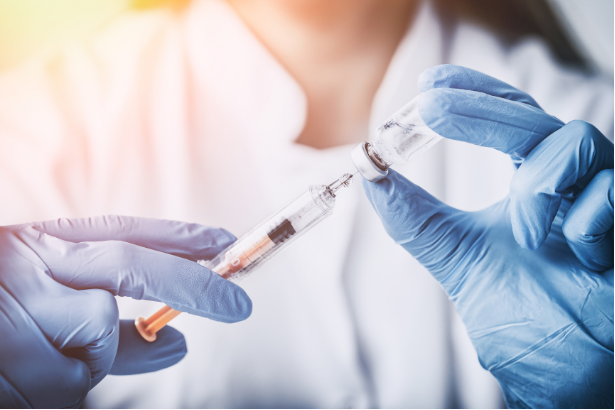 Syringe inserted into vial of drug